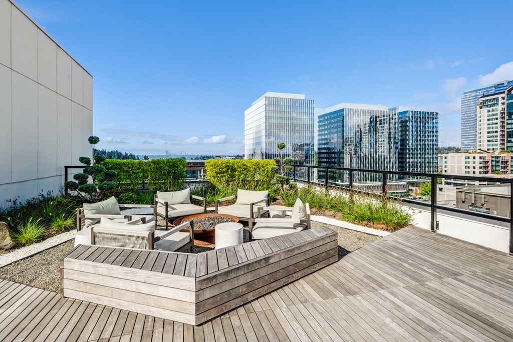A wooden deck with a table and chairs overlooks a cityscape.
